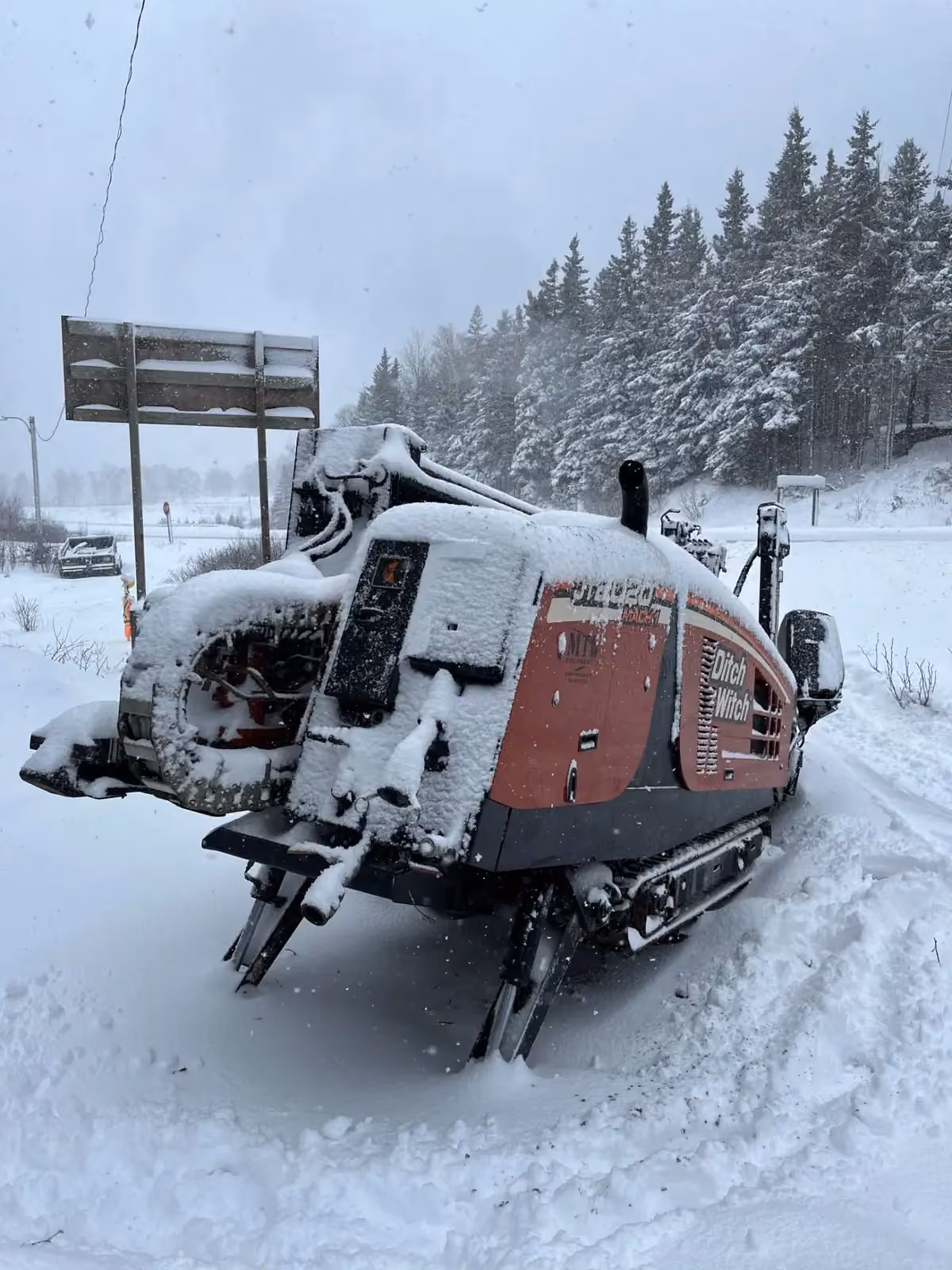 Snow-covered directional drill rig set up for a winter highway crossing