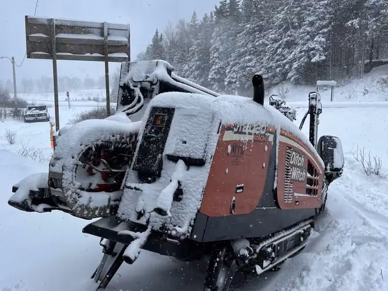 Snow-covered directional drill rig set up for a winter highway crossing